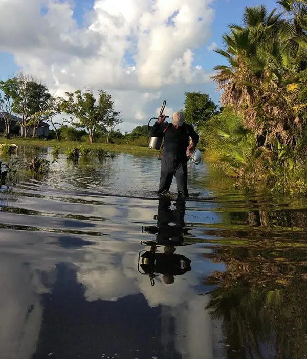 A malaria worker walks through water.