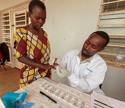 A health worker performs a blood test on a woman to test for hepatitis C.