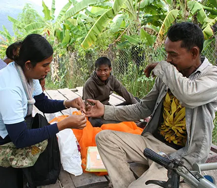 Malaria worker pricks a man's finger to perform a rapid blood test.
