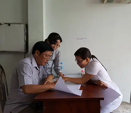 Health workers look at papers over a desk.
