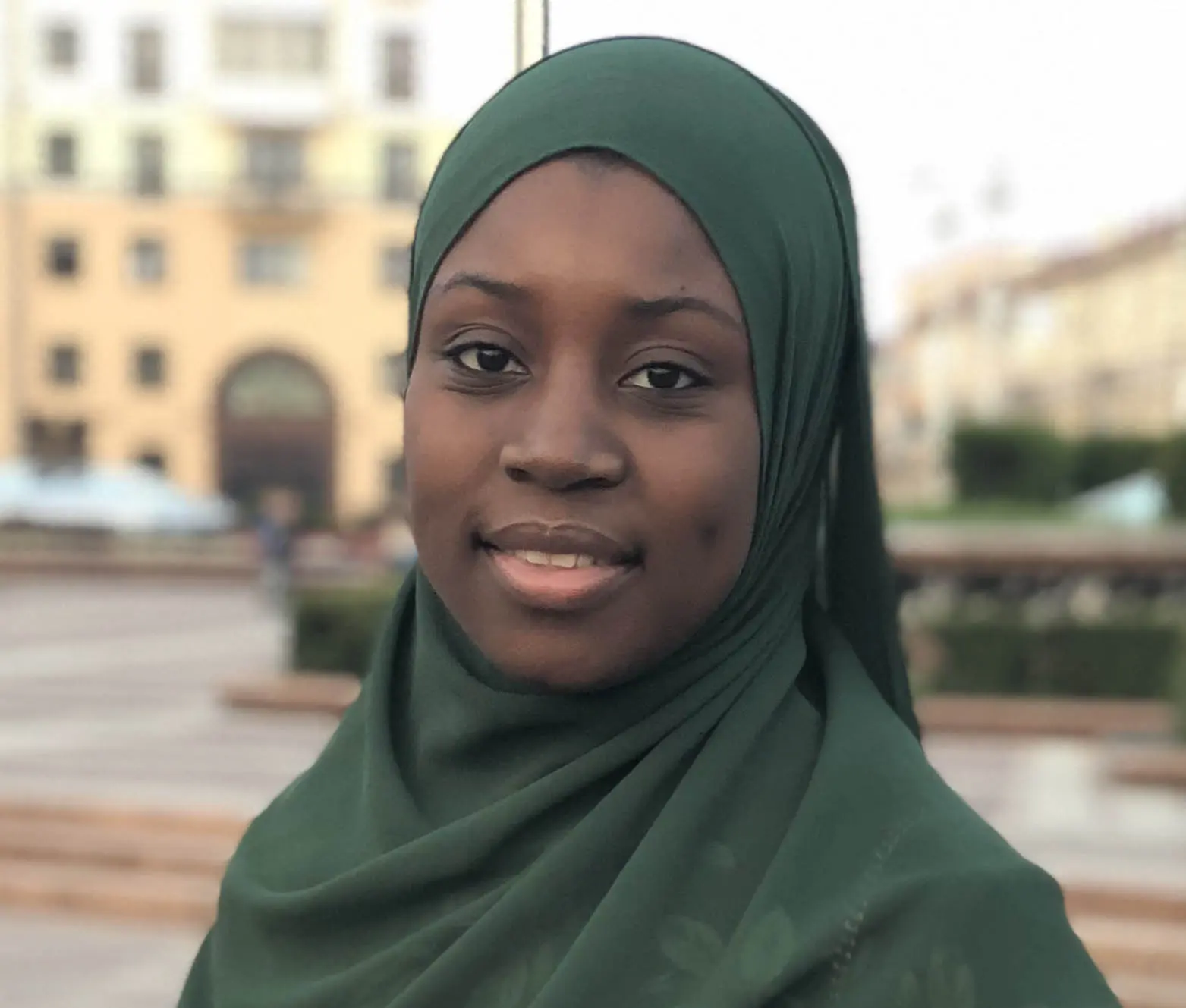 Aisha stands outside.