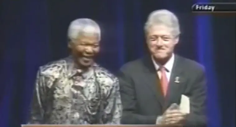 Former South African and US presidents Nelson Mandela and Bill Clinton stand on stage after speaking at IAS 2002.