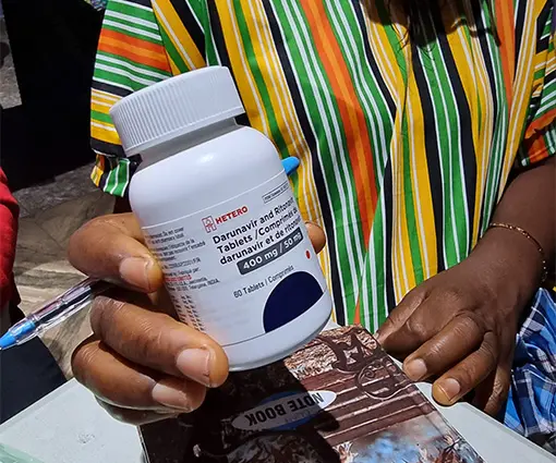 A white bottle of medication being held by a Nigerian person