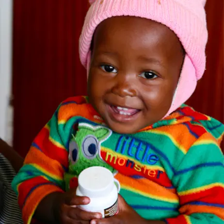 Smiling child holding a bottle of medicine