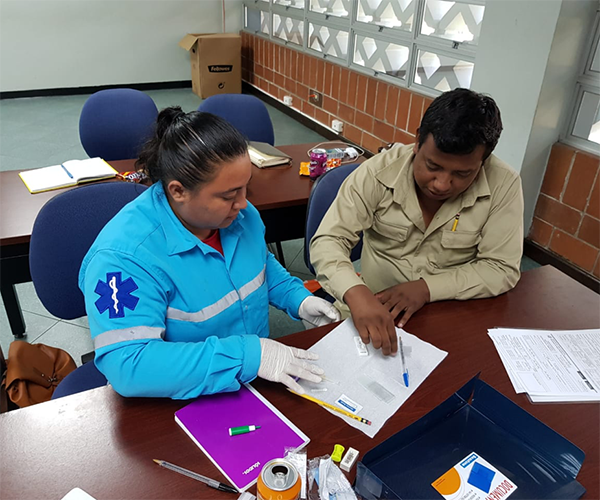 A health worker performs a malaria test on an agricultural worker.