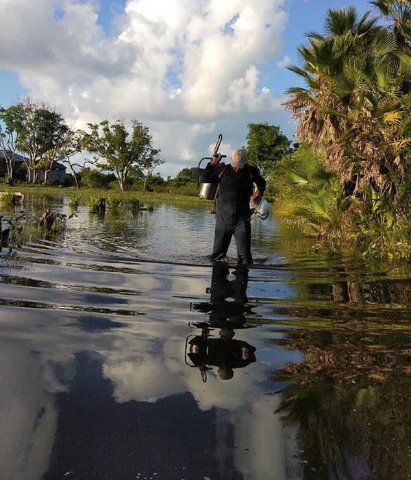 A malaria worker walks through water.