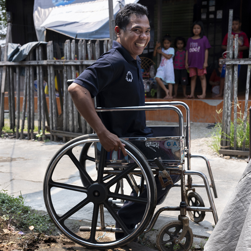 Full shot of Ahmad Fitri from Indonesia sitting on a wheel chair. Image by Angus Stewart as part of the Global Disability Innovation Hub's AT2030 programme