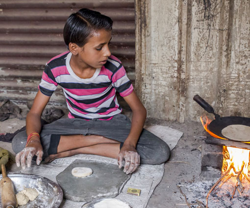 A young boy cooks chapati at home.