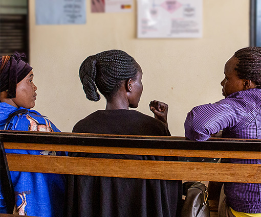 Three women talk in a health centre waiting room.