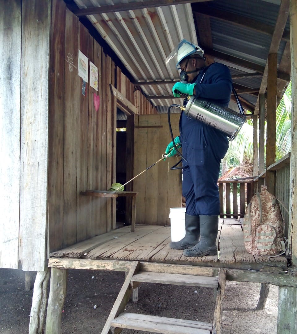 Health worker in Honduras sprays house with mosquito insecticide