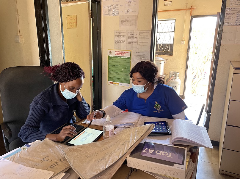 Health workers in Zimbabwe evaluate data on a mobile device