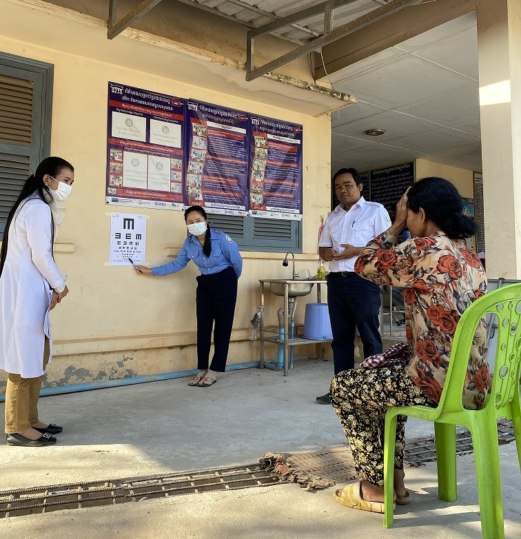 A Cambodian elderly lady covers one eye with her hand as her eye sight is tested