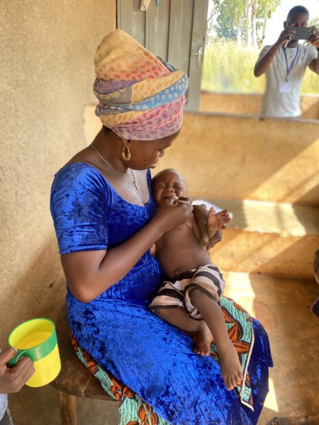 A mother gives a child antimalaria medicine in Benin