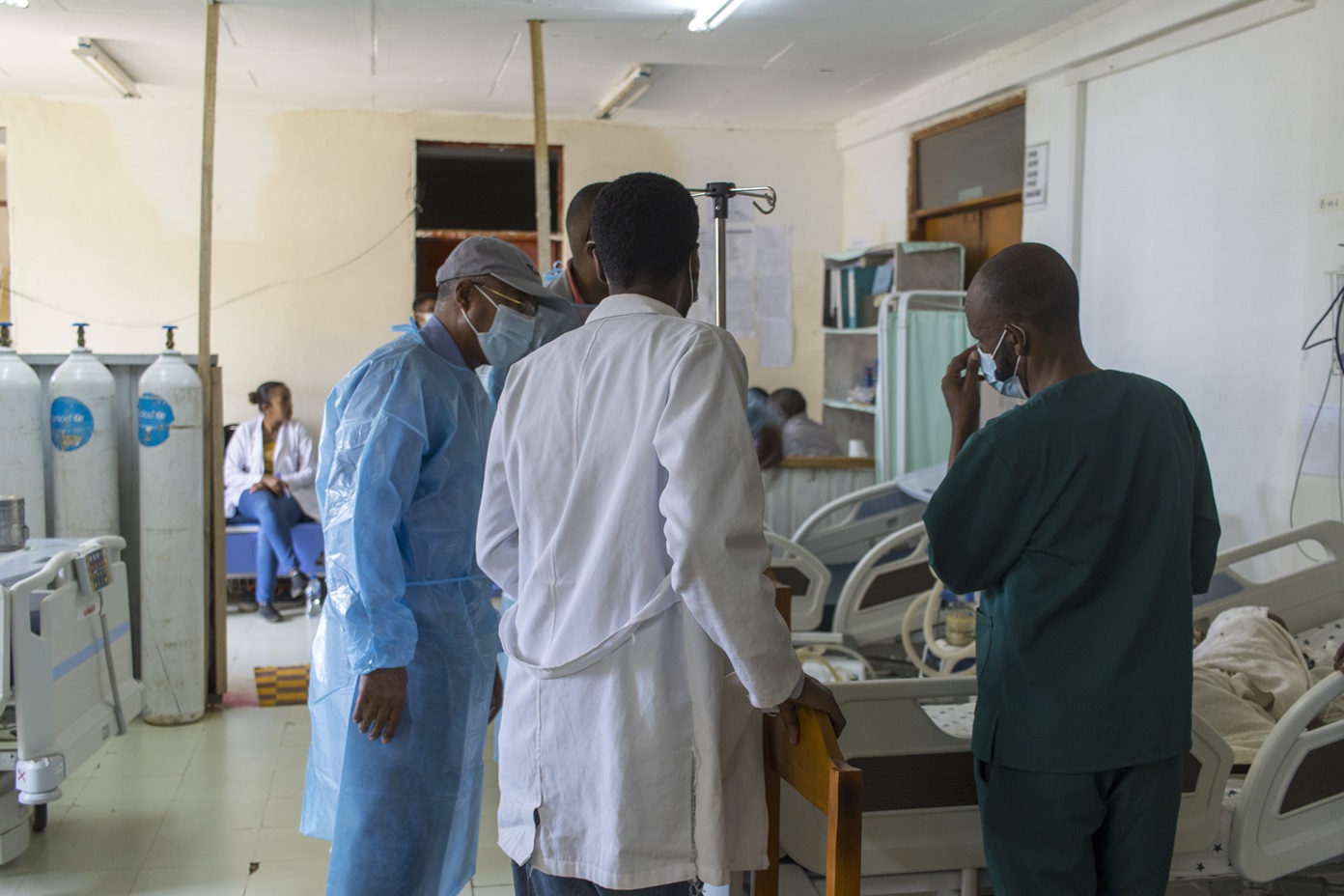 Four health workers, including a doctor stand at the end of a baby's bed at Bonga Hospital ICU, Ethiopia. Further in the room, you can see three oxygen tanks