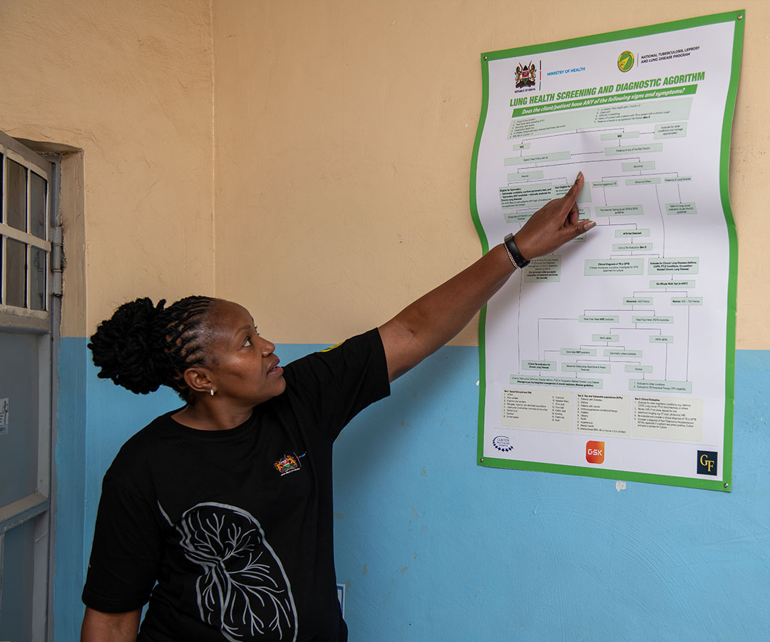 A healthcare worker in Kenya points to a poster about lung health screening procedure